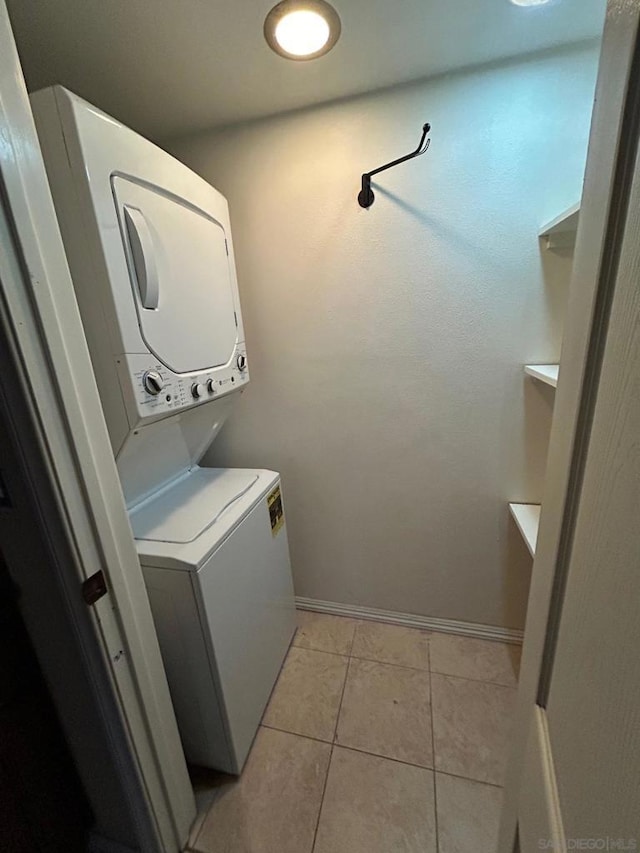 clothes washing area featuring stacked washer and dryer and light tile patterned flooring