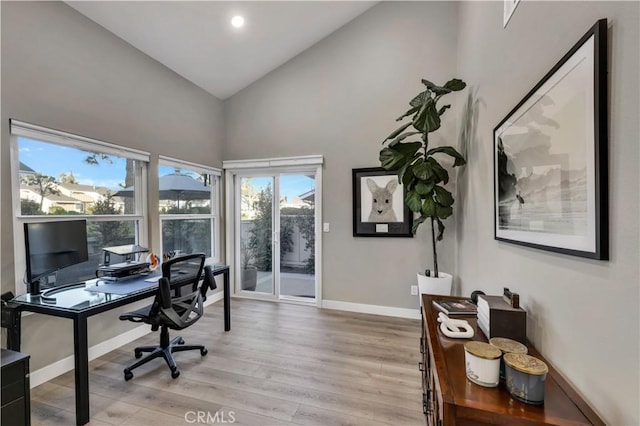 office with high vaulted ceiling and light wood-type flooring