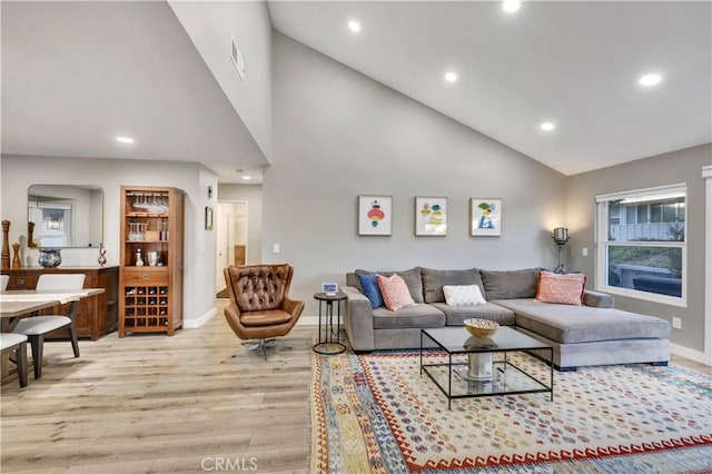 living room with light hardwood / wood-style flooring and high vaulted ceiling