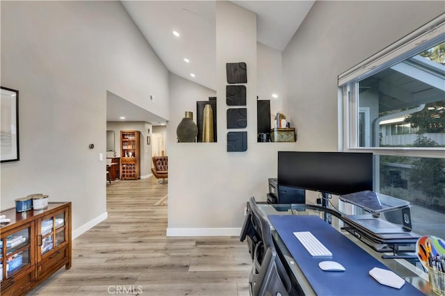 office space with plenty of natural light, high vaulted ceiling, and light wood-type flooring