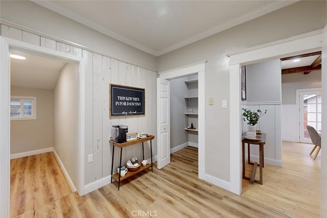 corridor with ornamental molding and light hardwood / wood-style flooring