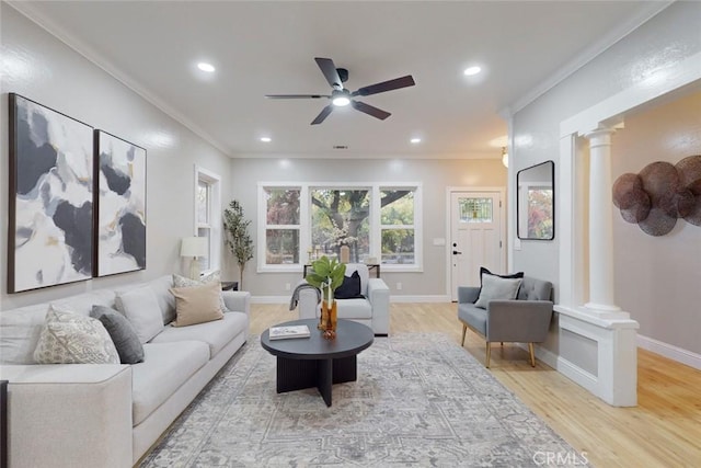 living room with ceiling fan, light wood-type flooring, ornate columns, and crown molding