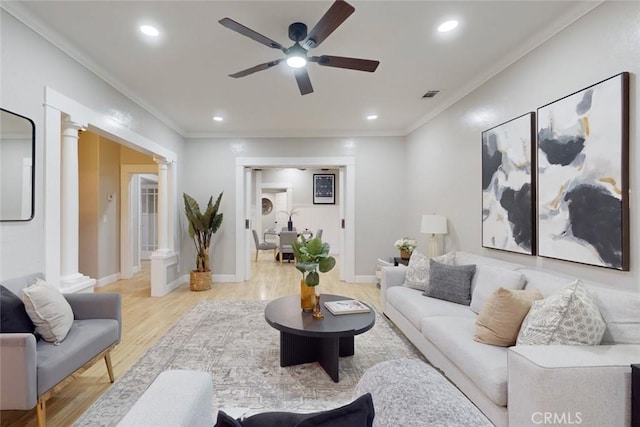 living room with decorative columns, light hardwood / wood-style flooring, ceiling fan, and crown molding