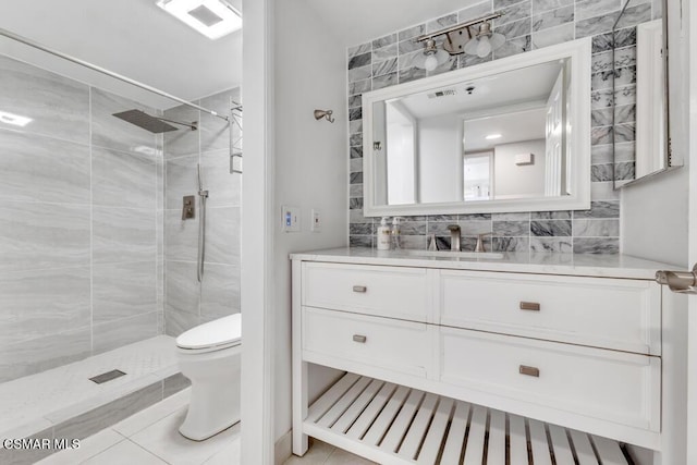 bathroom featuring tile patterned floors, vanity, toilet, and tiled shower