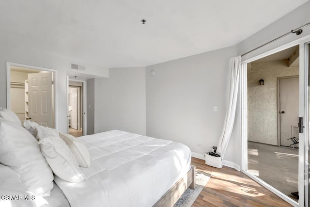 bedroom with a walk in closet, light wood-type flooring, and a closet