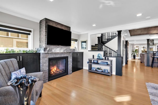 living room with a fireplace, ornamental molding, and light hardwood / wood-style flooring