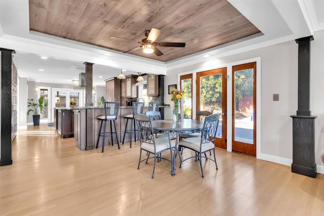 dining space with ornate columns, a raised ceiling, light wood-type flooring, ceiling fan, and wooden ceiling