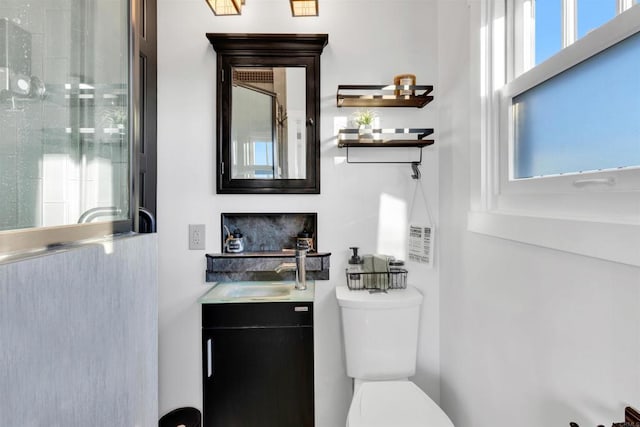 bathroom with toilet, vanity, a wealth of natural light, and walk in shower