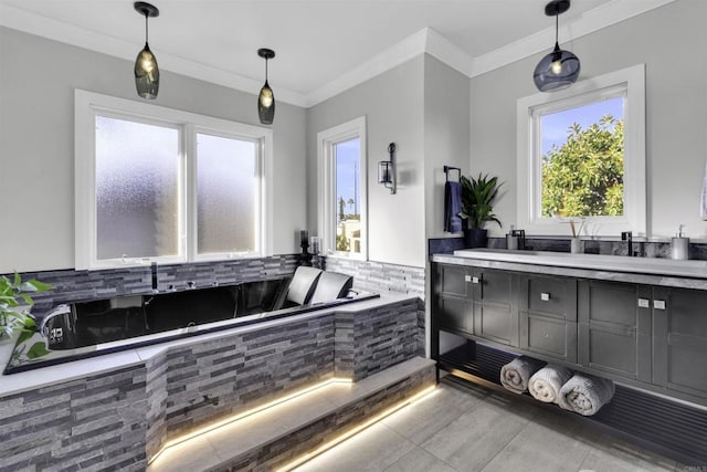 bathroom with tiled bath, a wealth of natural light, vanity, and crown molding