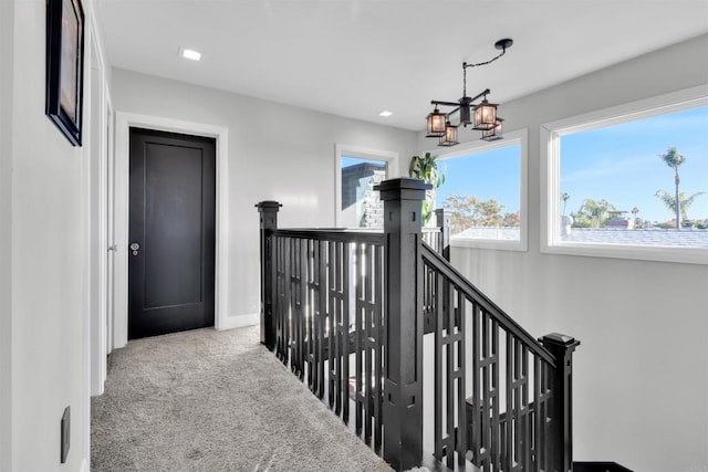 corridor with a chandelier and light colored carpet