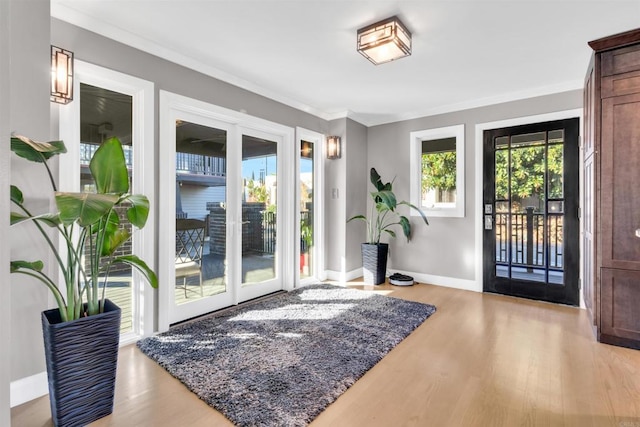 doorway featuring crown molding and light hardwood / wood-style floors