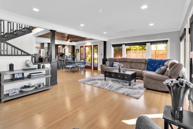 living room with ceiling fan, crown molding, and light wood-type flooring