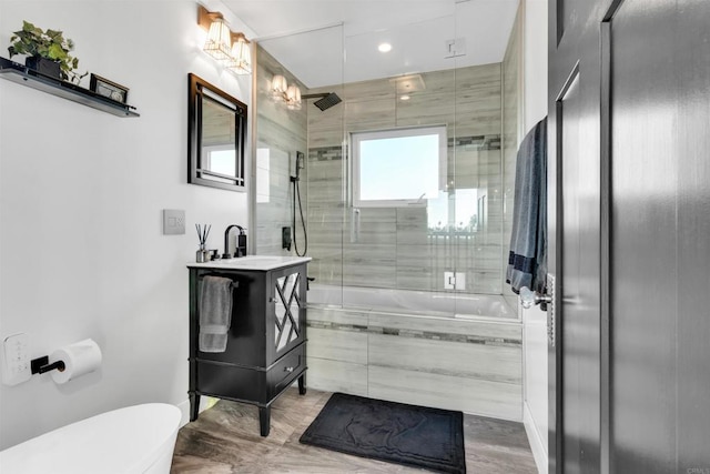 full bathroom with tiled shower / bath combo, vanity, toilet, elevator, and hardwood / wood-style flooring