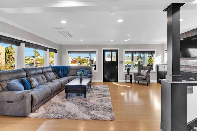 living room featuring plenty of natural light, crown molding, ornate columns, and light hardwood / wood-style flooring