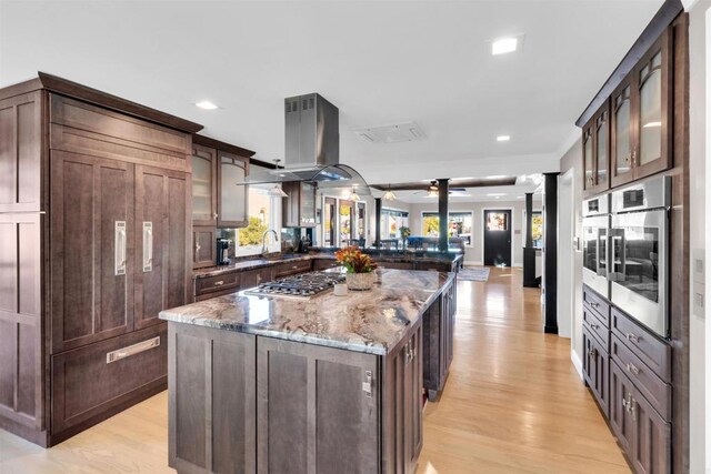 kitchen featuring a peninsula, ceiling fan, light wood finished floors, glass insert cabinets, and recessed lighting