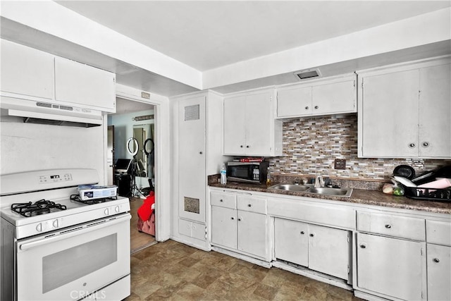 kitchen featuring dark countertops, white range with gas stovetop, white cabinetry, and a sink