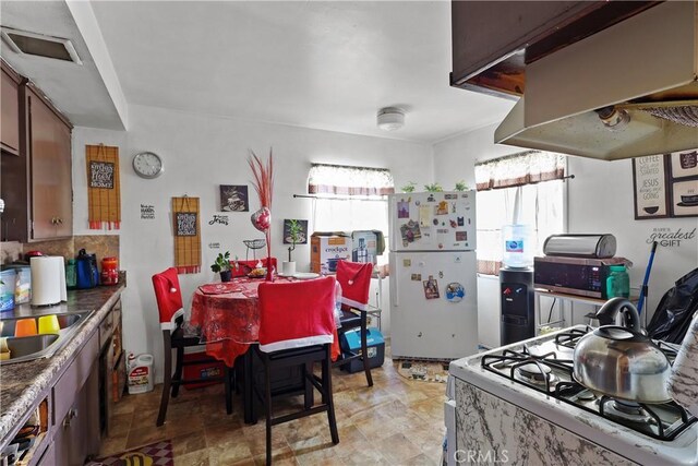 kitchen featuring white appliances, a sink, visible vents, backsplash, and island exhaust hood