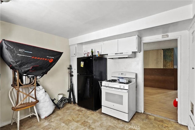 kitchen with under cabinet range hood, white gas range oven, white cabinetry, and freestanding refrigerator