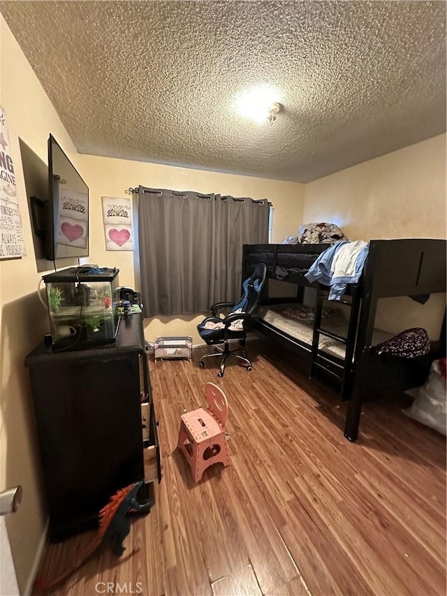 bedroom with a textured ceiling and wood finished floors