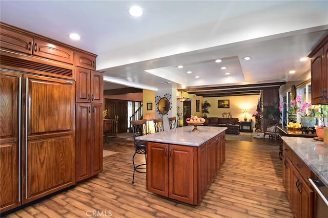 kitchen with a center island, a breakfast bar, paneled built in refrigerator, and light wood-type flooring