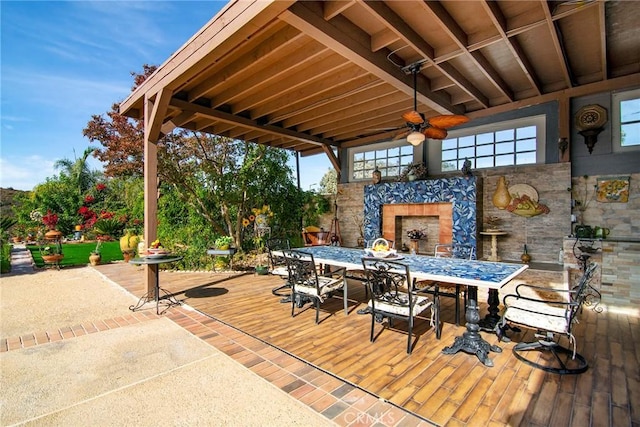 wooden deck with ceiling fan, a patio, and exterior fireplace