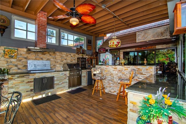 kitchen featuring dark stone countertops, ceiling fan, dark hardwood / wood-style flooring, and plenty of natural light