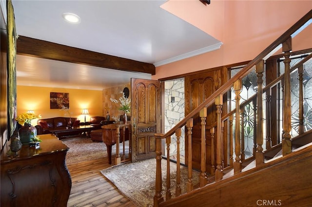 entrance foyer featuring light hardwood / wood-style floors, crown molding, and beam ceiling