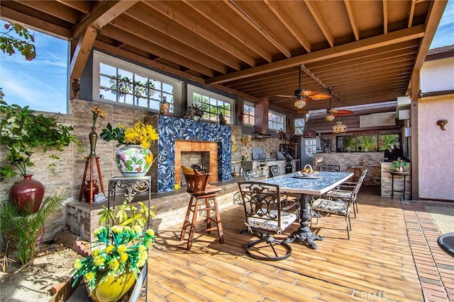 wooden terrace featuring ceiling fan and an outdoor stone fireplace