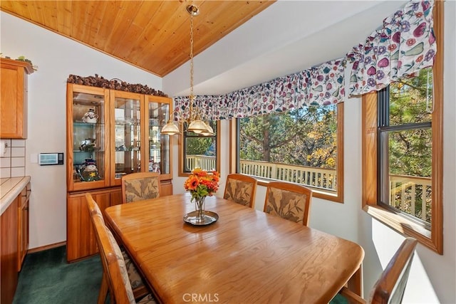 dining space with dark colored carpet, a healthy amount of sunlight, wood ceiling, and vaulted ceiling