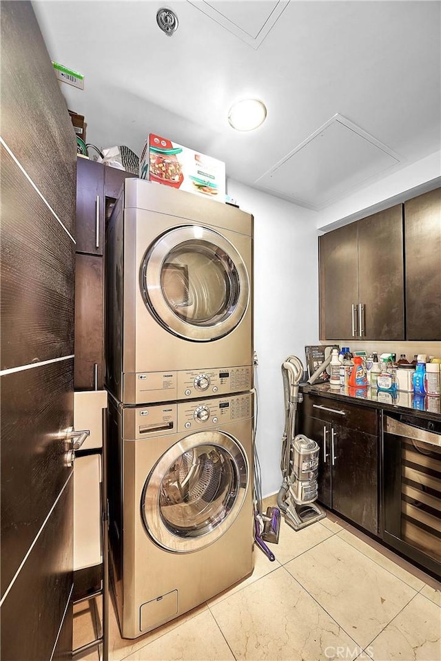 laundry room with cabinets, stacked washing maching and dryer, wine cooler, and light tile patterned flooring