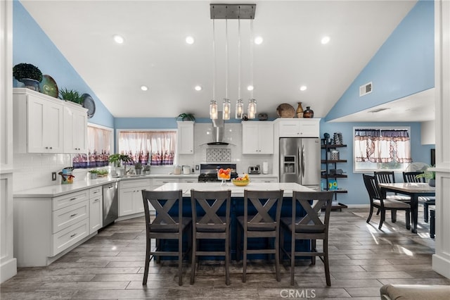 kitchen with backsplash, appliances with stainless steel finishes, a kitchen island, and pendant lighting