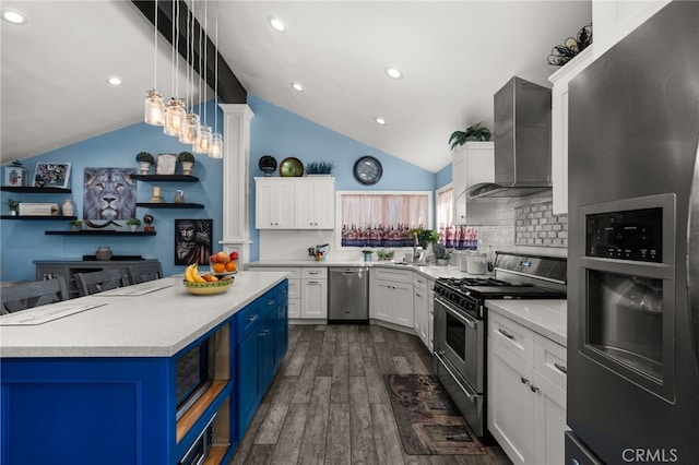 kitchen featuring tasteful backsplash, pendant lighting, stainless steel appliances, white cabinets, and wall chimney exhaust hood