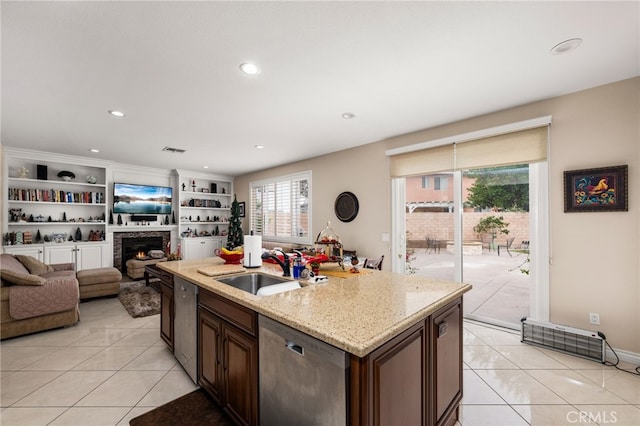 kitchen featuring sink, light tile patterned flooring, stainless steel dishwasher, and a center island with sink