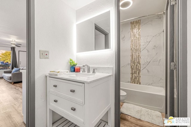 full bathroom featuring vanity, ceiling fan, hardwood / wood-style flooring, toilet, and tiled shower / bath