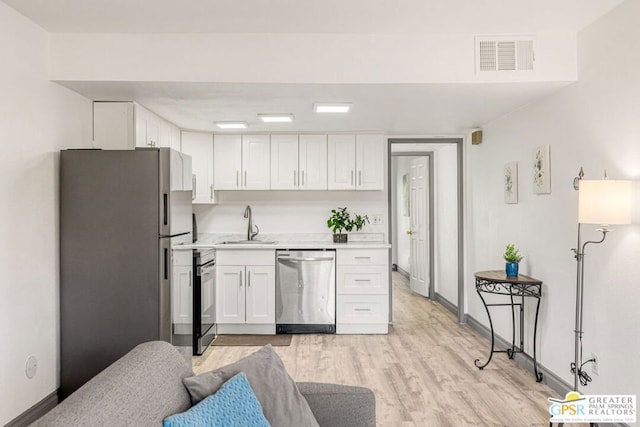 kitchen with light wood-type flooring, white cabinetry, sink, and appliances with stainless steel finishes