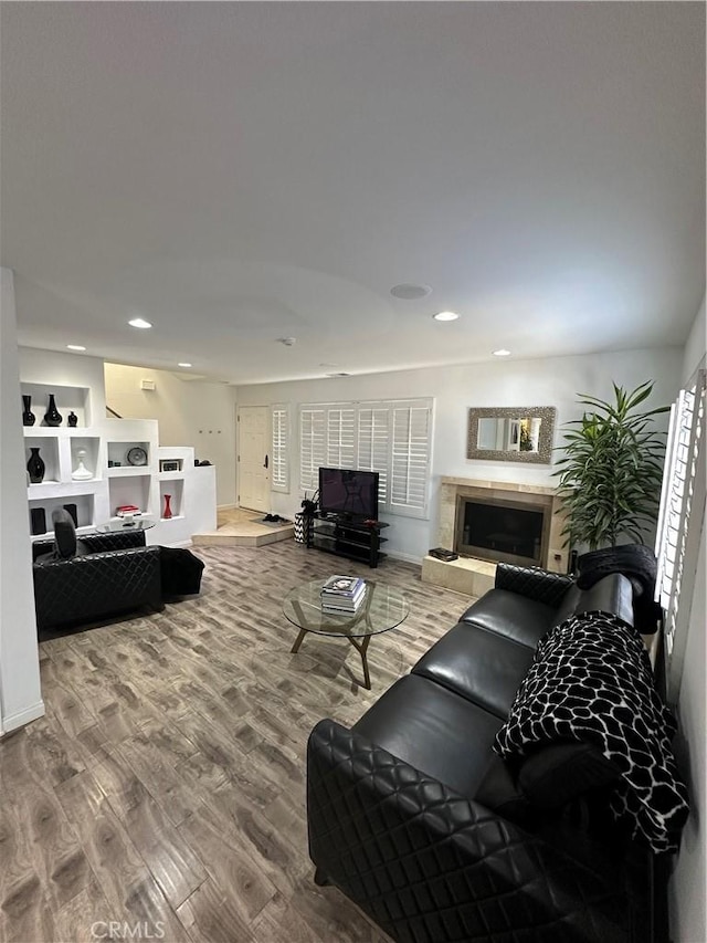living room with wood finished floors, a fireplace, baseboards, and recessed lighting