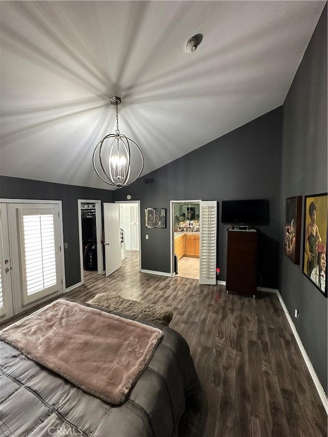 bedroom with ensuite bathroom, a chandelier, vaulted ceiling, a walk in closet, and hardwood / wood-style flooring