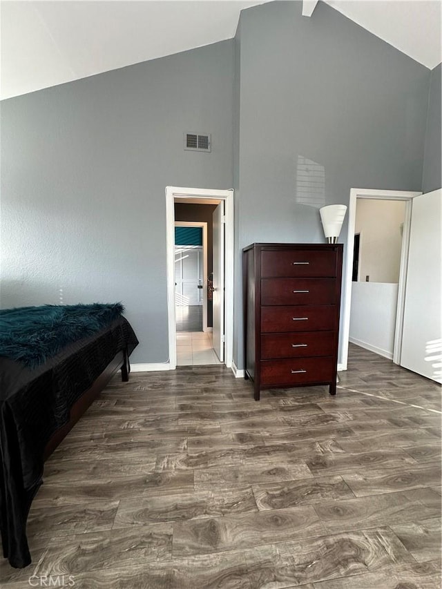 bedroom featuring connected bathroom, dark hardwood / wood-style floors, and high vaulted ceiling