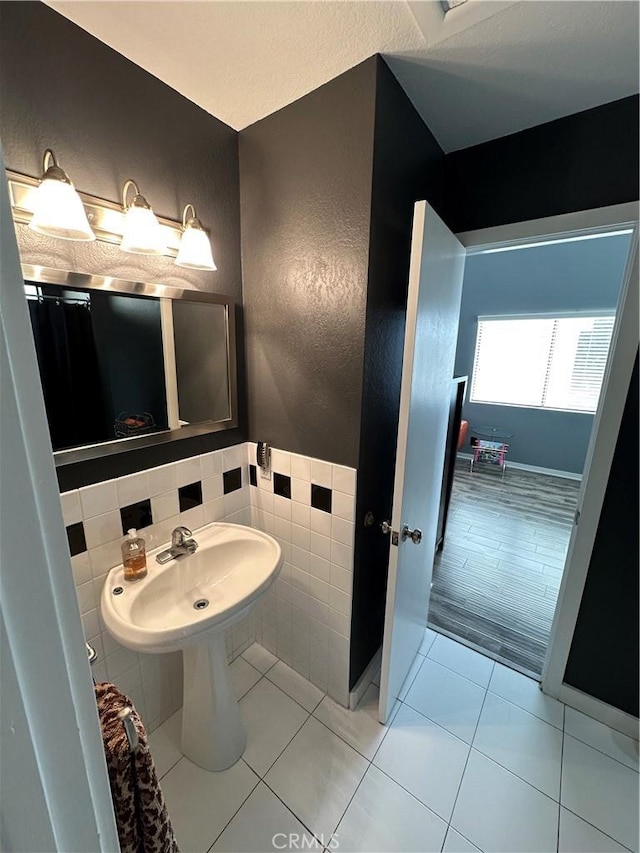 bathroom featuring a sink, tile walls, tile patterned floors, and a textured wall