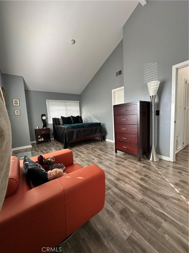 bedroom featuring high vaulted ceiling, visible vents, baseboards, and wood finished floors