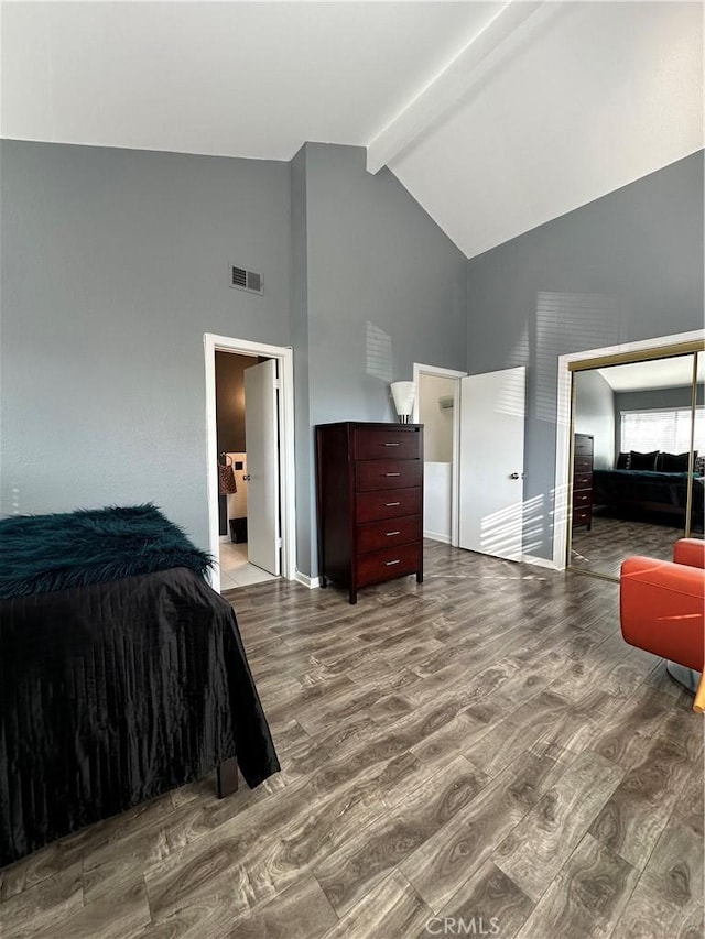 bedroom featuring beamed ceiling, high vaulted ceiling, hardwood / wood-style flooring, and ensuite bath