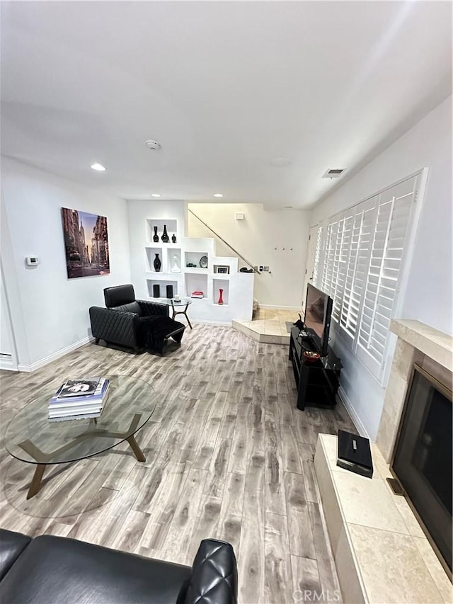 living room featuring wood finished floors, a fireplace, baseboards, and recessed lighting