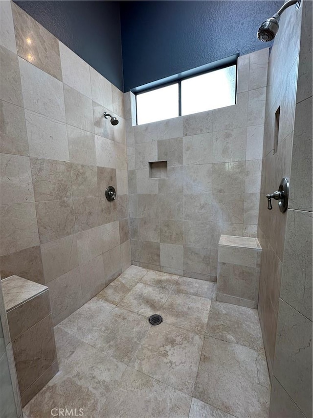 bathroom featuring a tile shower and a healthy amount of sunlight