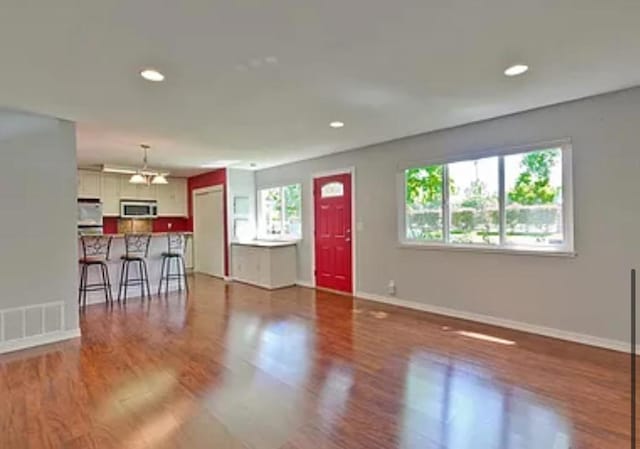 unfurnished living room with an inviting chandelier and wood-type flooring