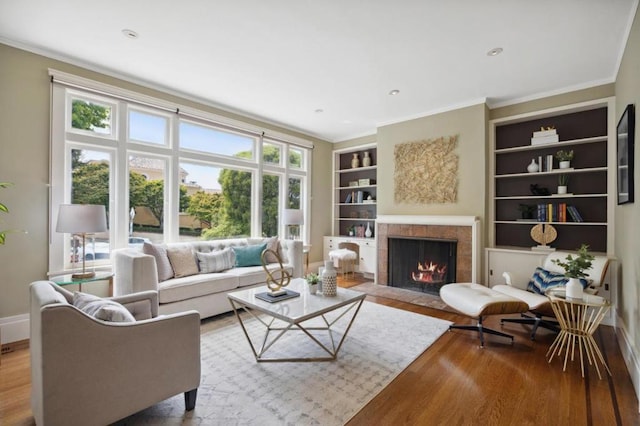 living room featuring crown molding, plenty of natural light, light hardwood / wood-style flooring, and built in shelves