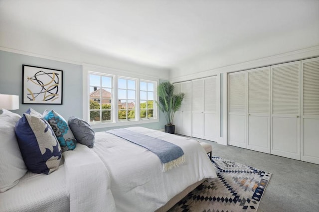 bedroom with multiple closets and carpet flooring