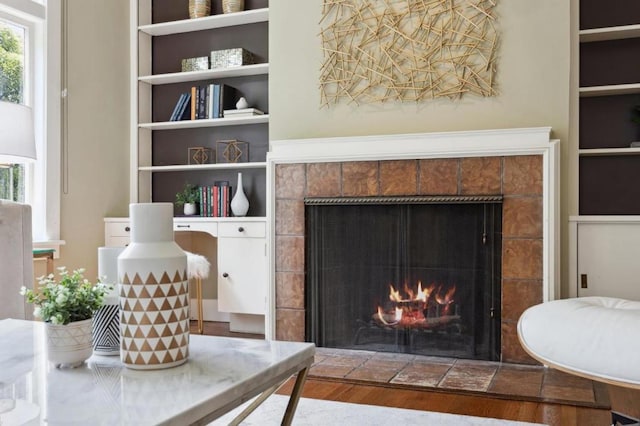 living room featuring a tiled fireplace, hardwood / wood-style floors, and built in features