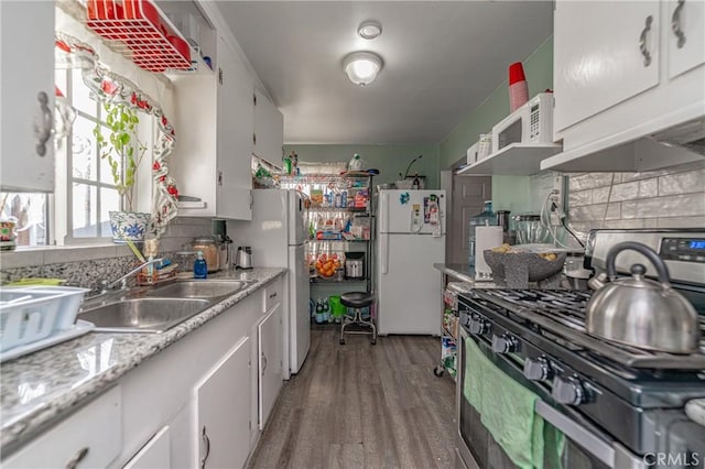 kitchen with white cabinets, sink, hardwood / wood-style flooring, stainless steel gas stove, and white fridge