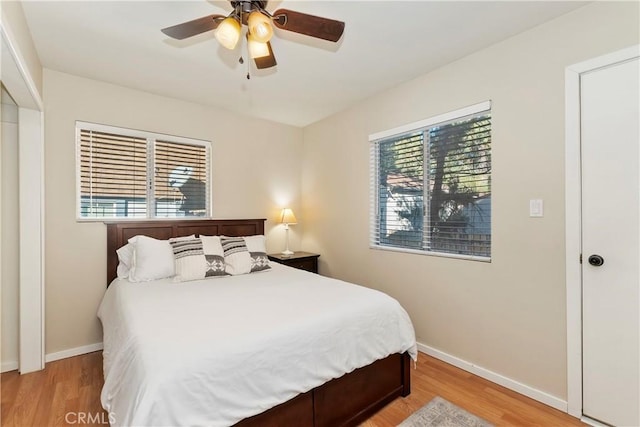 bedroom with ceiling fan, light hardwood / wood-style flooring, and multiple windows