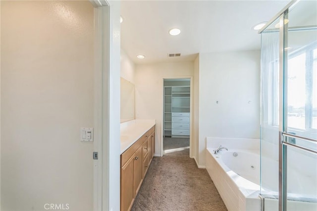 bathroom with vanity and a relaxing tiled tub